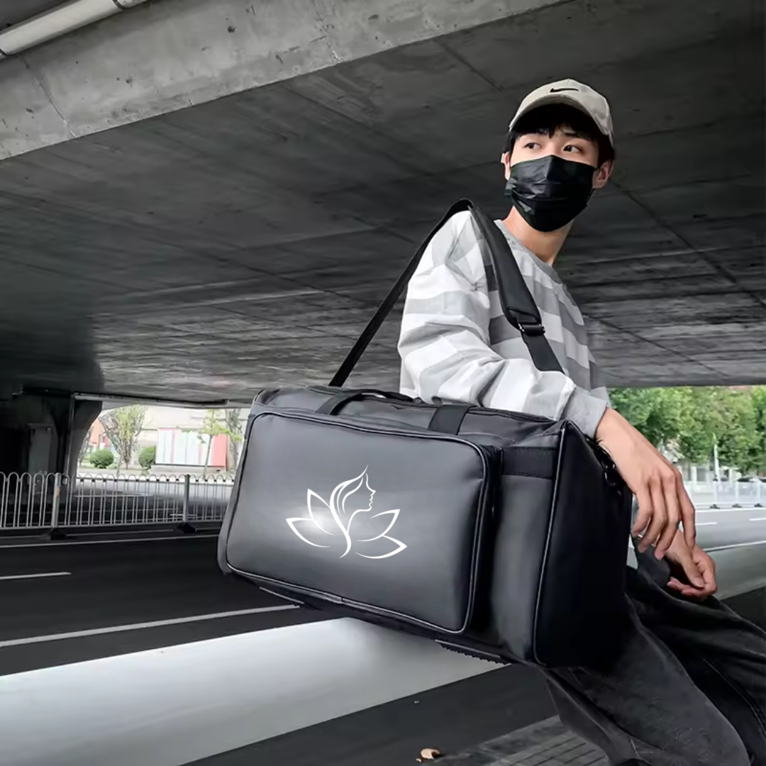Person sitting on a car with a black duffel bag featuring a white logo, wearing a face mask.